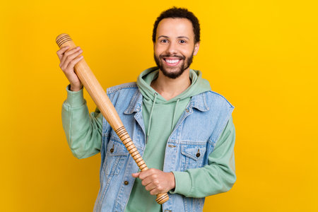 Photo portrait of handsome young male hold baseball bet smiling dressed stylish khaki outfit isolated on yellow color backgroundの写真素材