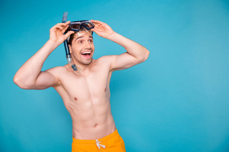 Photo of dreamy impressed shirtless man going snorkeling looking empty space isolated blue color backgroundの写真素材