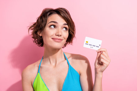Closeup photo of young addicted shopaholic woman holding new plastic debit card dreaming look mockup isolated on pink color backgroundの写真素材