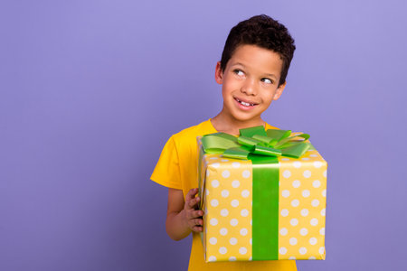 Photo of dreamy cute boy wear yellow stylish looking up empty space special offer clothes isolated on purple color backgroundの写真素材