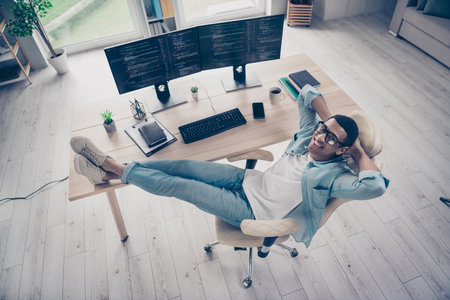 Photo of handsome professional it specialist having rest end buy day put legs on desktop relaxing...