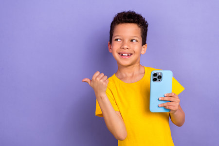 Photo of cute preteen age latin boy wear yellow trendy clothes thumb recommend buy novelty empty space isolated on purple color backgroundの写真素材