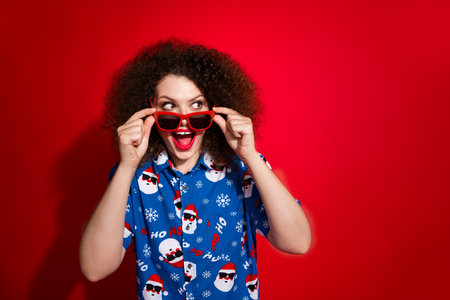 Photo portrait of lovely young lady look interested empty space wear trendy blue print x-mas garment isolated on red color backgroundの写真素材