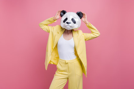 Photo of cool classy costume girl hands touch 3d panda mask mardi gras event party isolated on pink color backgroundの写真素材