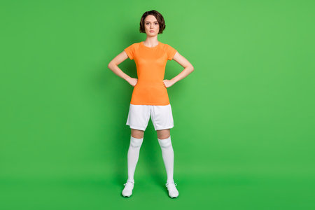 Full length portrait of pretty girl standing put hands fists on waist look camera isolated on green color backgroundの写真素材