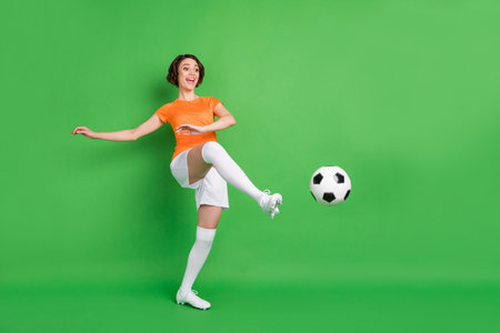 Full size portrait of positive person look empty space foot kick ball have fun isolated on green color backgroundの写真素材
