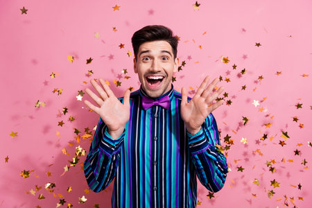 Portrait of astonished classy person raise opened hands palms flying confetti isolated on pink color backgroundの写真素材