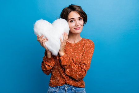 Photo portrait of attractive young woman hold white fluffy pillow dressed stylish brown clothes isolated on blue color backgroundの写真素材