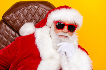 Portrait of minded creative charismatic aged santa sit chair hand touch beard brainstorming christmas isolated on yellow color backgroundの写真素材