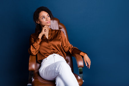 Photo portrait of attractive young woman serious business plan dressed stylish brown silk formalwear isolated on dark blue color backgroundの写真素材