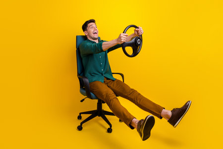 Photo of cheerful funky man dressed stylish clothes looking empty space fast speed test drive lesson isolated on yellow color backgroundの写真素材
