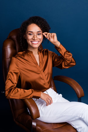 Vertical photo of attractive young woman working manager ceo dressed stylish brown silk formalwear isolated on dark blue color backgroundの写真素材