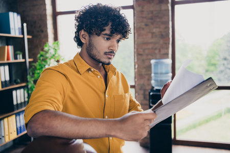 Photo portrait of attractive young man wear yellow shirt boss read employee report modern workplace...