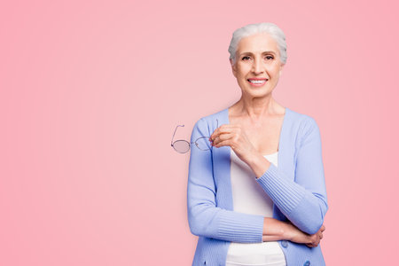 Granny advises Beautiful nice gray-haired smiling old lady business woman wearing casual, holding glasses. Copy space. Isolated over pastel violet purple backgroundの写真素材