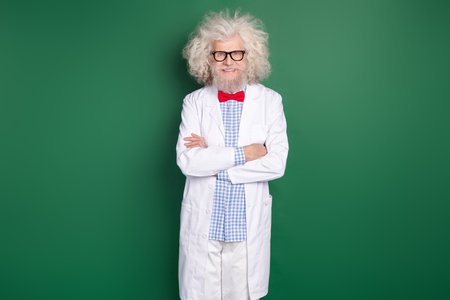 Photo of happy funky funny smiling crazy scientist wear long white coat crossed arms isolated on green color backgroundの写真素材