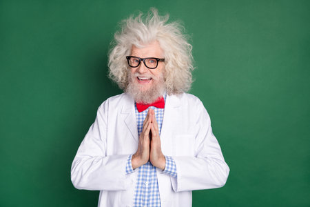 Photo of happy smiling funky funny crazy scientist hold hands in anticipation excitement isolated on green color backgroundの写真素材