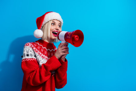 Photo of attractive excited lady santa helper dressed ornament sweater screaming bullhorn empty space isolated blue color backgroundの写真素材