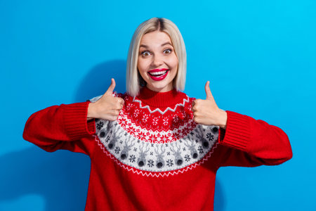 Portrait of astonished attractive lady beaming smile demonstrate thumb up approval isolated on blue color backgroundの写真素材