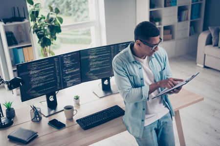 Photo of young ponder man it specialist programmer reading paper documents notepad checking business plan startup in loft style officeの写真素材