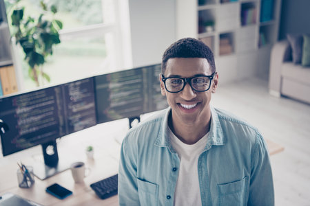 Portrait photo of young funny man successful javascript coder toothy smiling in his home office outsource worker wear eyeglasses indoorsの写真素材