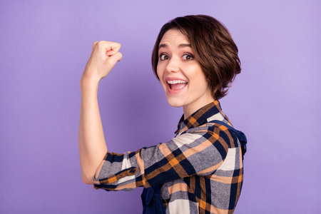 Profile side photo of young woman happy positive smile technician show hand biceps power isolated over violet color backgroundの写真素材