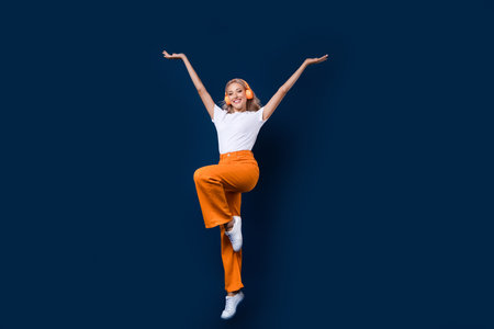 Photo of cheerful lovely girl wear stylish clothes raise hands enjoy summer weekend cool party isolated on dark blue color backgroundの写真素材