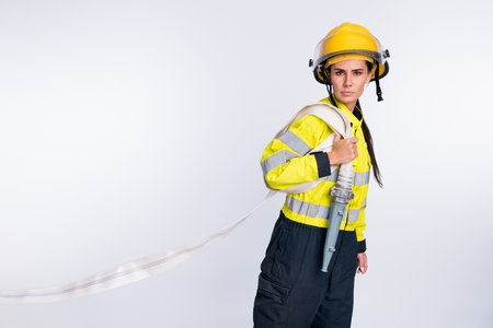 Profile side photo of young woman firefighter hold hose water urgency protection isolated over white color backgroundの写真素材