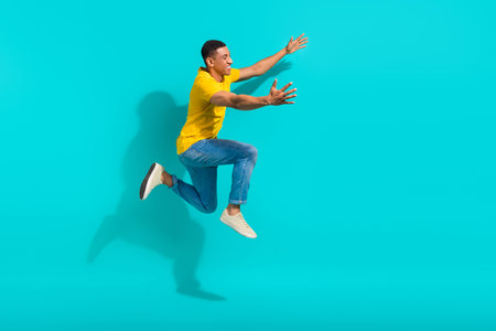 Full length profile photo of energetic crazy person jump rush hurry raise opened arms empty space isolated on teal color backgroundの写真素材