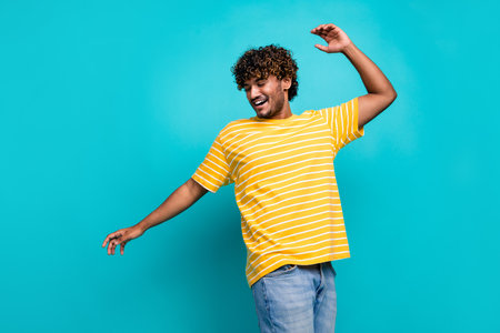 Portrait of overjoyed carefree young man enjoy dancing partying have good mood isolated on cyan color backgroundの写真素材