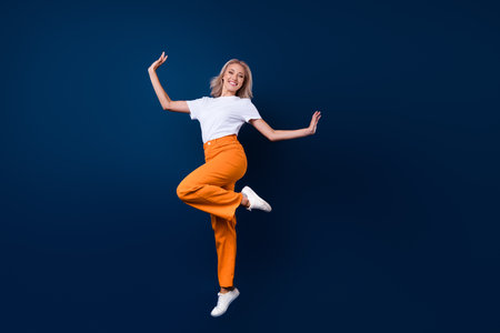 Full length photo of stunning cute elegant girl wear trendy outfit jump up empty space isolated on dark blue color backgroundの写真素材