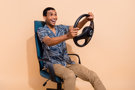 Photo of sweet handsome man wear print shirt driving car fast smiling isolated beige color backgroundの写真素材