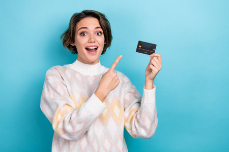 Photo portrait of lovely young lady excited promo finger point credit card dressed stylish white garment isolated on blue color backgroundの写真素材
