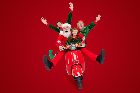 Photo of nice glad excited team four people ride moped raise hands wear santa elf costume isolated...