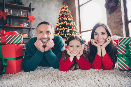 Full length photo of positive nice people hands touch cheeks lying carpet floor festive giftbox tree illumination indoorsの写真素材