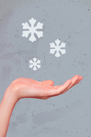 Vertical collage image of person arm palm catch falling snowflakes isolated on creative painted winter grey backgroundの写真素材