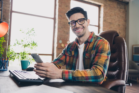 Photo of cheerful it company ceo sitting chair use smart phone networking modern business center workstation indoorsの写真素材
