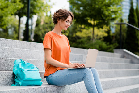 Photo of sweet adorable lady wear orange t-shirt spectacles remote education modern gadget outside urban city streetの写真素材