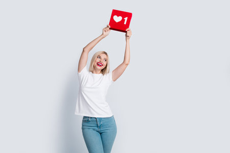 Portrait of good mood girl with blond hairdo wear t-shirt look at social media like in hands over...
