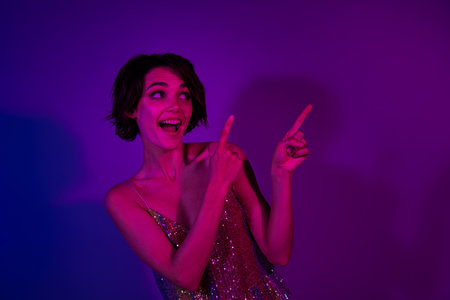 Photo of amazed lady feel positive about festive occasion indicate empty space isolated neon color backgroundの写真素材