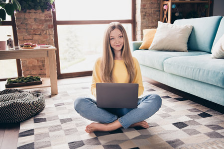Full body photo of teenager barefoot girl using netbook when learning it courses sitting floor isolated on home decoration backgroundの写真素材