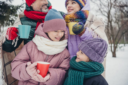 Photo of sweet adorable little child wife husband dressed coats covering blanket drinking hot beverages outdoors urban forest parkの写真素材