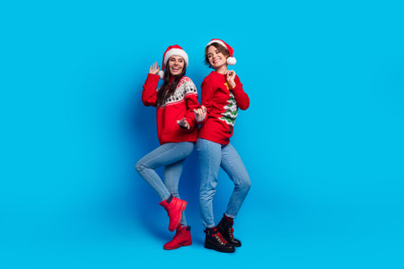 Full length photo of pretty cheerful ladies santa helpers dressed print sweaters dancing xmas...