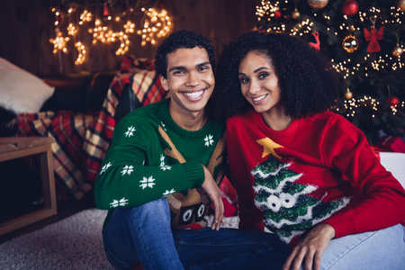 Photo of charming friends couple lady guy enjoy christmas time together under illuminated fir tree in cozy room indoorsの写真素材