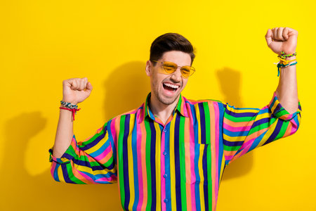 Photo of carefree boyfriend in striped colorful shirt macho sunglasses and hand bracelets enjoy...