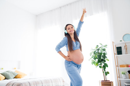 Photo of cheerful glad lovely energetic pregnant girl with big tummy enjoy free time weekend alone white light room indoorsの写真素材