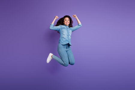 Full body photo of delighted nice lady jumping raise fists attainment empty space isolated on violet color backgroundの写真素材