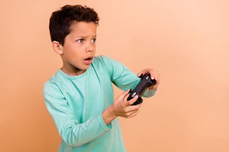 Photo of sad upset boy wear trendy clothes have fun video game online look empty space isolated on beige color backgroundの写真素材