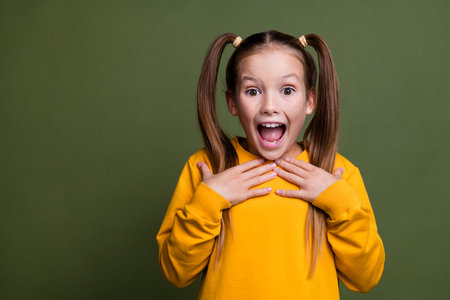 Portrait of impressed kid with tails dressed yellow shirt staring at unbelievable offer empty space isolated on khaki color backgroundの写真素材