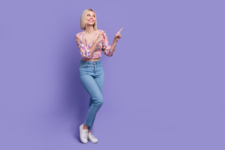 Full body photo of stunning positive lady look direct fingers empty space isolated on violet color backgroundの写真素材