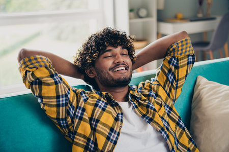 Photo of cheerful carefree person it sofa closed eyes arms behind head free time chilling house indoorsの写真素材